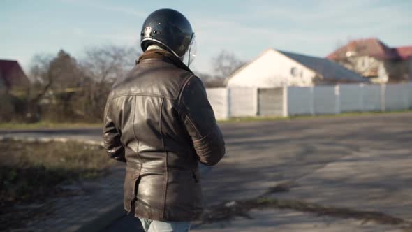 A Young Man Goes to His Motorcycle Sits on It and Puts a Helmet to Go on a Journey