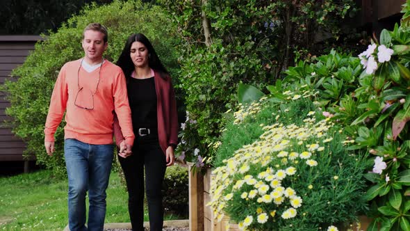 Young Latin couple walks through the garden with beautiful flowers in a very relaxed