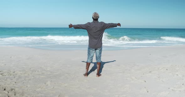Senior man raising his arms at the beach