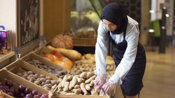 Woman in Hijab Refill the Potatos on the Stock at the Supermarket