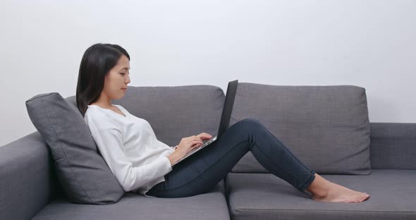 Woman work on computer and lying on sofa