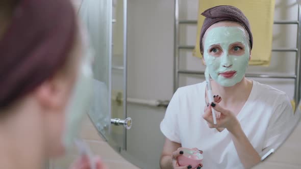 Woman Applying Cosmetic Facial Mask in Bathroom Look at Mirror Spbas