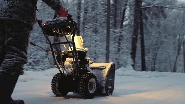 Snowcovered Man Cleans the Road in Winter with Blower Snow Removal Equipment
