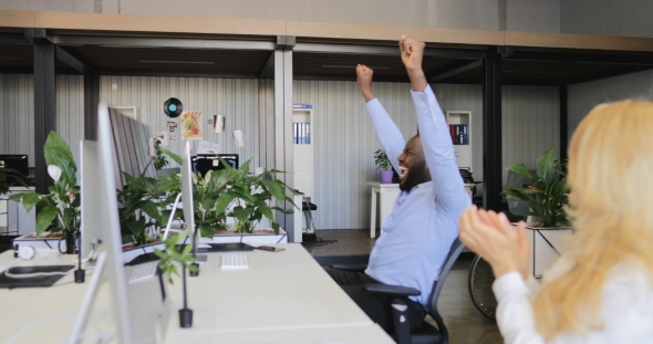 Cheerful African American Business Man Celebrating Success Sit At Computer In Modern Coworking