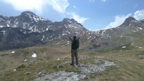 Hiker Stands on Top and Keeps His Hands Raised in a Gesture of Victory