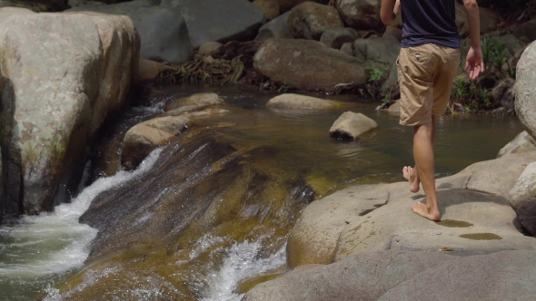 Tourist Puts His Feet in the River Flowing Between Big Stones in Jungles