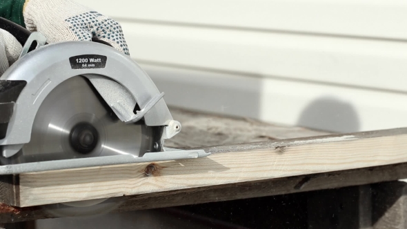 Worker in Gloves Cutting a Wooden Plank with Hand Circular Saw