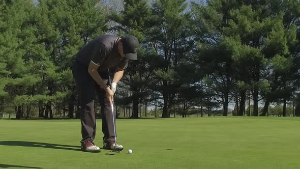 golfer putts the ball into the hole slow motion