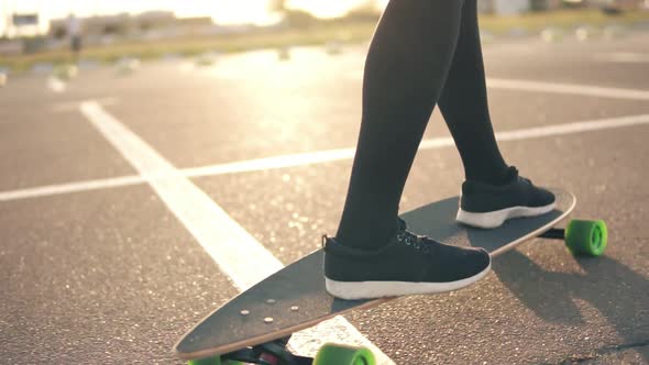 Closeup View of Woman's Legs in Black Sneakers and Long Socks Skateboarding on the Road in the City