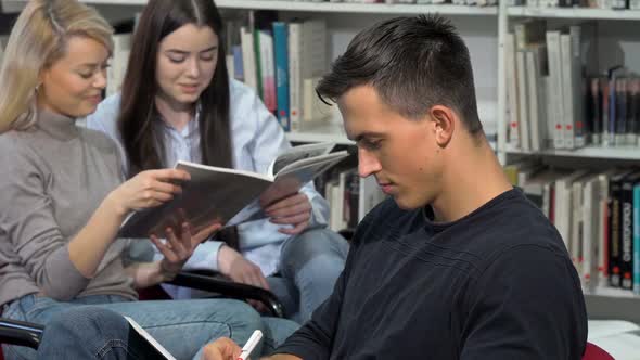 Handsome Male Student Smiling To the Camera, While Doing Homework at Library