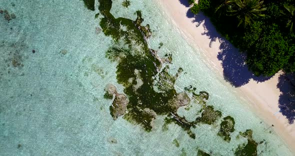 Tropical fly over abstract shot of a sandy white paradise beach and aqua blue water background 