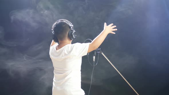 Back View Of A Young Boy With Headphone Rapping On The White Smoke Black Background