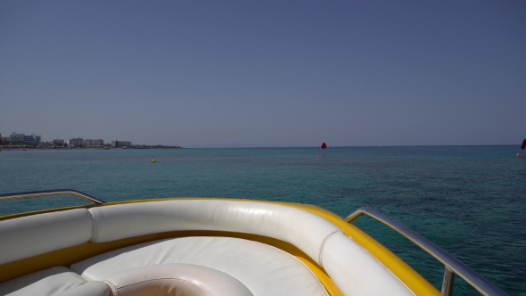 Motorboat Moves Away From Beach in Blue Sea