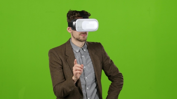 Boy in Virtual Glasses Looks at Imaginary Photographs and Smiles. Green Screen