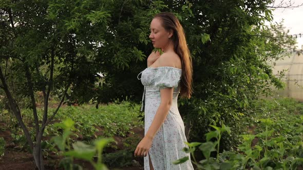 Woman Walking in Garden with Green Plants