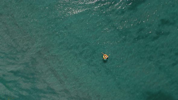 Aerial Drone Top View of Turquoise Sea Water and Relaxed Woman Swimming on Yellow Floating Swim Ring