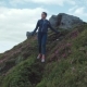 Young Woman in Sport Wear Goes Down the Path on the Top of the Mountain - VideoHive Item for Sale
