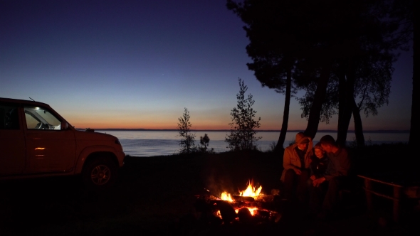 Family of Tree Around a Campfire at Night with Car