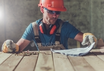 cumentation on the Wooden Table. Construction Worker Reviewing Docs.