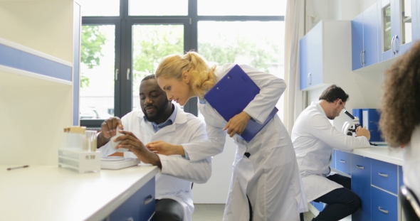 Scientist Woman Walking In Laboratory Watching At Results Of Researchers Mix Race Team Making