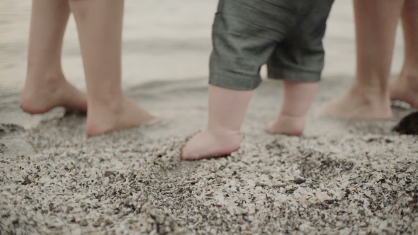 Baby First Steps on the Sand Whit Parents.  of Feet