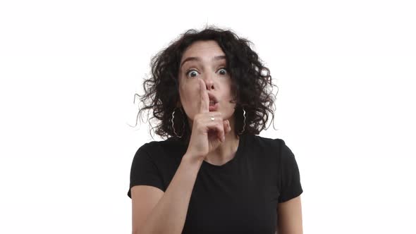 Annoyed and Bothered Woman with Curly Hairstyle Wearing Black Tshirt Shushing at Camera with Finger