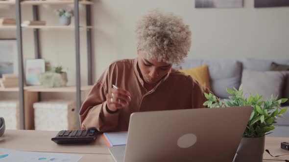 African Woman Calculates Domestic Bills Pay Loan Payments Online on Laptop