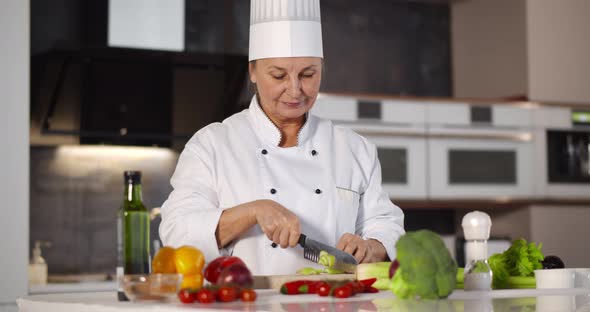 Portrait of Senior Woman Chef Cutting Vegetables in Modern Kitchen