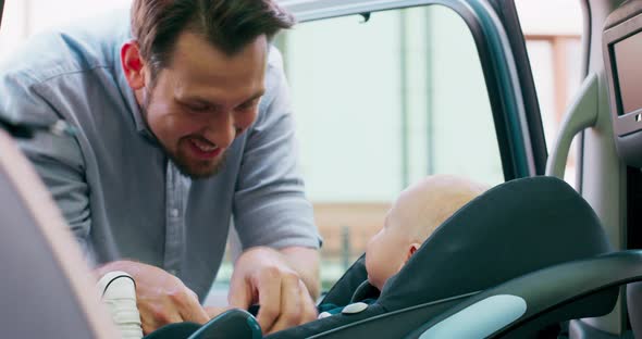 Closeup Baby Boy Who Sits in the Baby Car Seat Inside of Family Car Door Opens and His Smiled