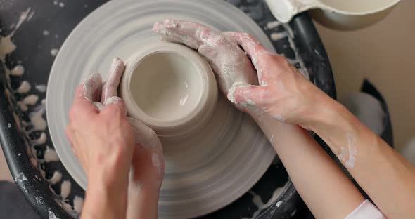 Hands of a Child Boy Who Sculpts Earthenware on a Potter's Wheel with the Help of Her Mother
