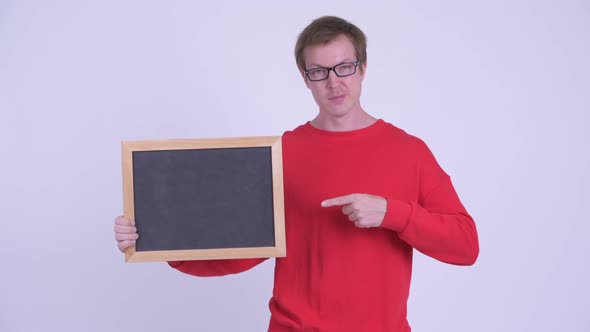 Happy Young Handsome Man Holding Blackboard and Giving Thumbs Up