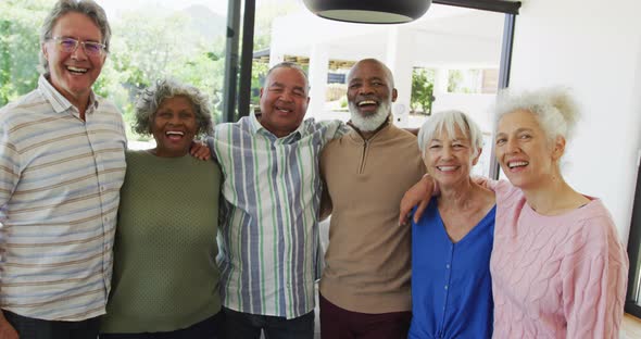 Portrait of happy senior diverse people embracing at retirement home