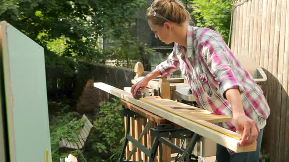 Woman measuring wooden plank with tape measure