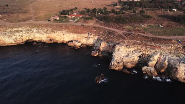 Drone top down aerial view of waves splash against rocky seashore, background. Flight over high clif