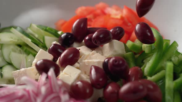 Camera follows putting fresh olive over greek salad. Slow Motion.