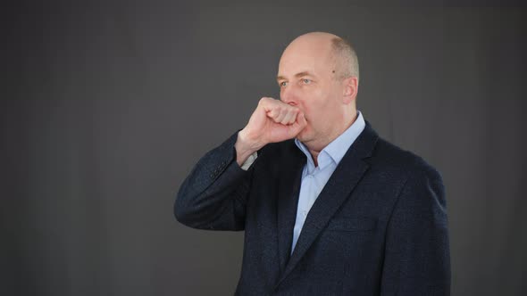 Sick Man Coughing Into Fist on Black Background in Studio. Cold Man Coughing Into Fist While Flu