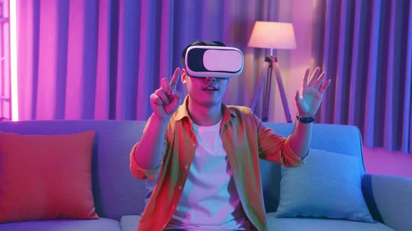 Asian Man Wearing Vr Headset At Living Room And Using Finger Touching , Cyan And Magenta Colors