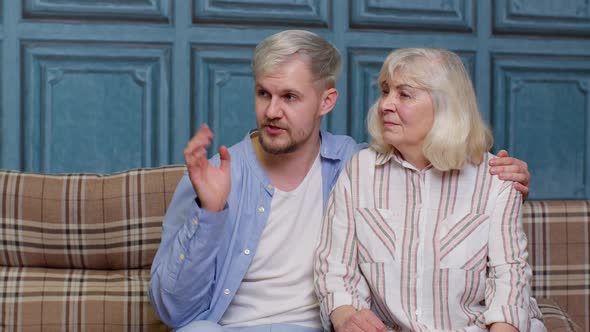 Family of Senior Mother Embracing Adult Son or Grandson and Having Hearttoheart Conversation