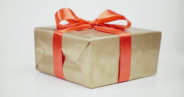 Present Wrapped with Golden Paper and Tied Red Ribbon Bow