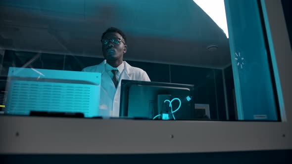 Black Skin Doctor in a White Robe Overseeing Surgery From the Control Room