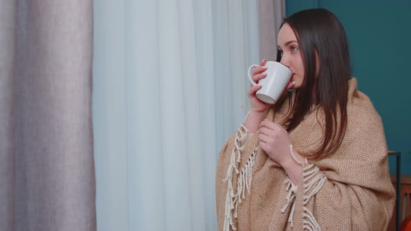 Young Adult Brunette Woman in Warm White Sweater Drink Hot Beverage Mug Relaxing at Home Near Window