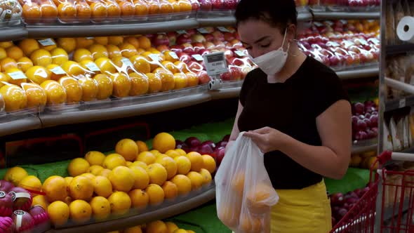 Young Woman in a Mask From a Coronavirus Epidemic is Standing in the Grocery Department of a