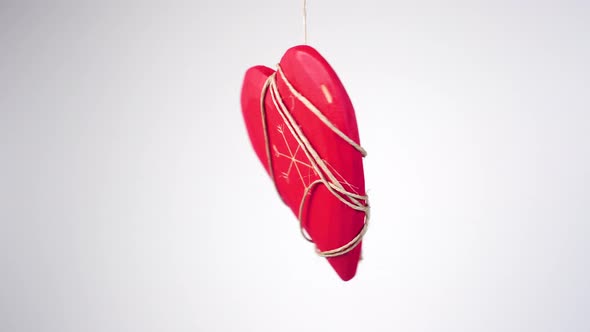 Red wooden heart entangled in a rope and hanging. 