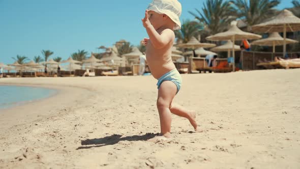 Active Toddler Running To Blue Water at Coastline. Little Boy Looking Camera