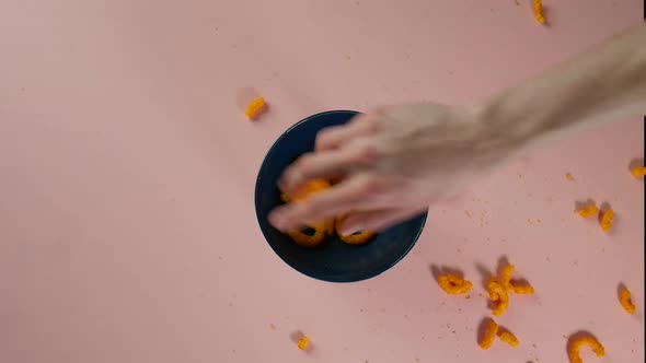 Top view of putting scattered cheese rings into a bowl