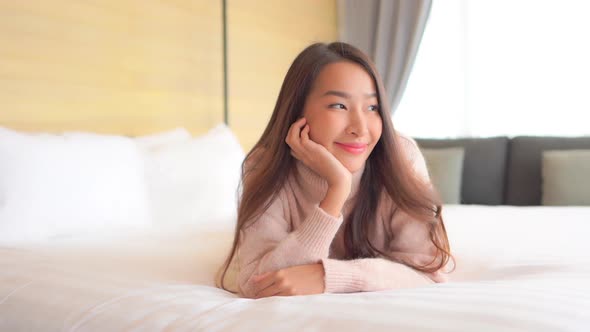 Asian woman relax on bed in bedroom interior