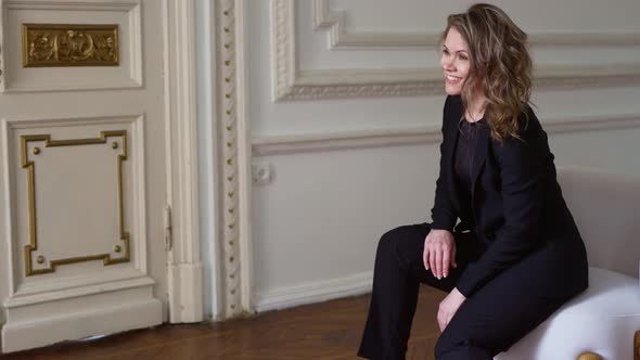 a Funny and Attractive Woman in a Black Suit in the Chair