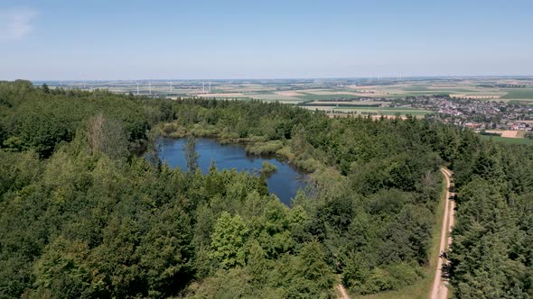 Establishing drone flight bird view of a lake in a forest and industry plants far in the background