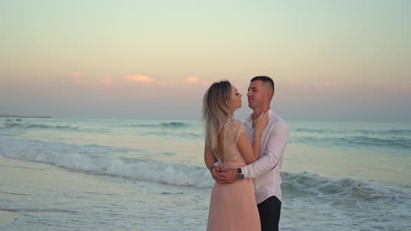 Romantic Couple on the Beach at Colorful Sunset on Background