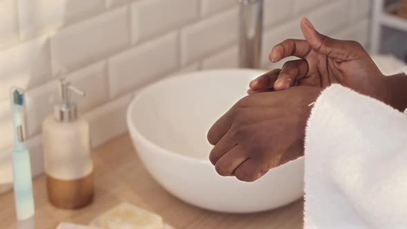 Woman Applying Cream on Face and Hands in Bathroom